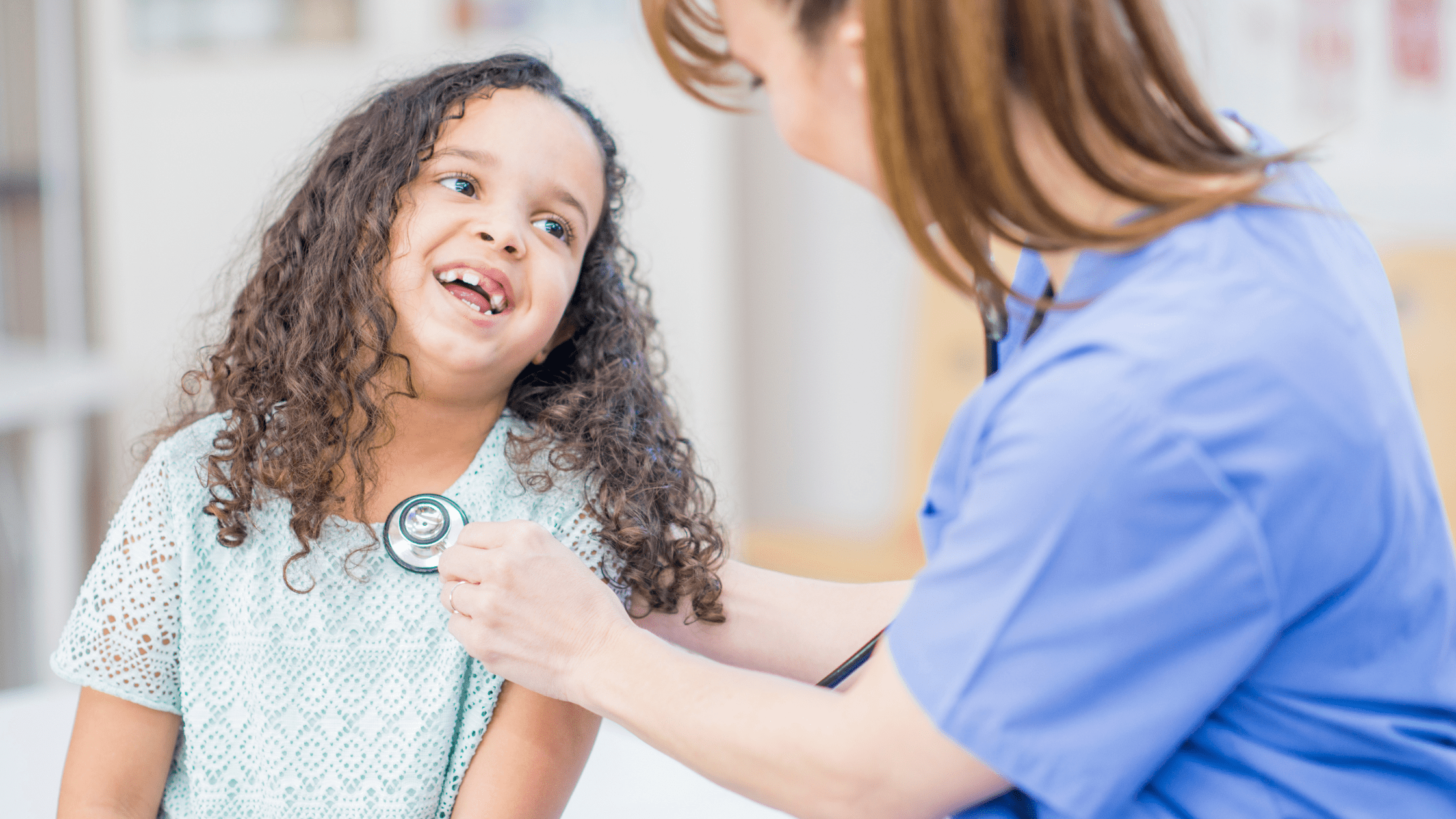 A pediatric resident checking in on her patient with a stethoscope.