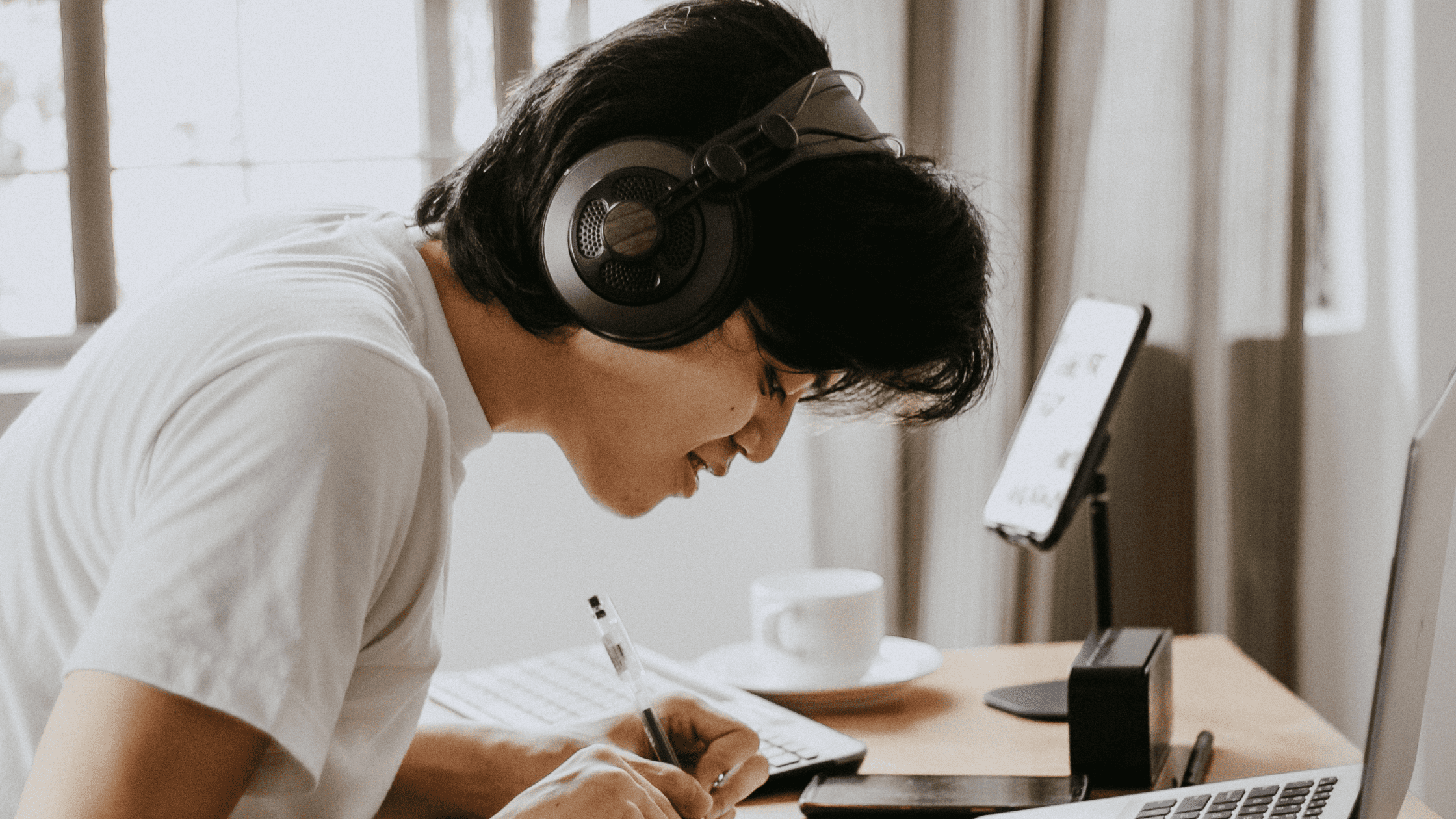 A student is sitting at a desk with headphones using MCAT Resources on his laptop