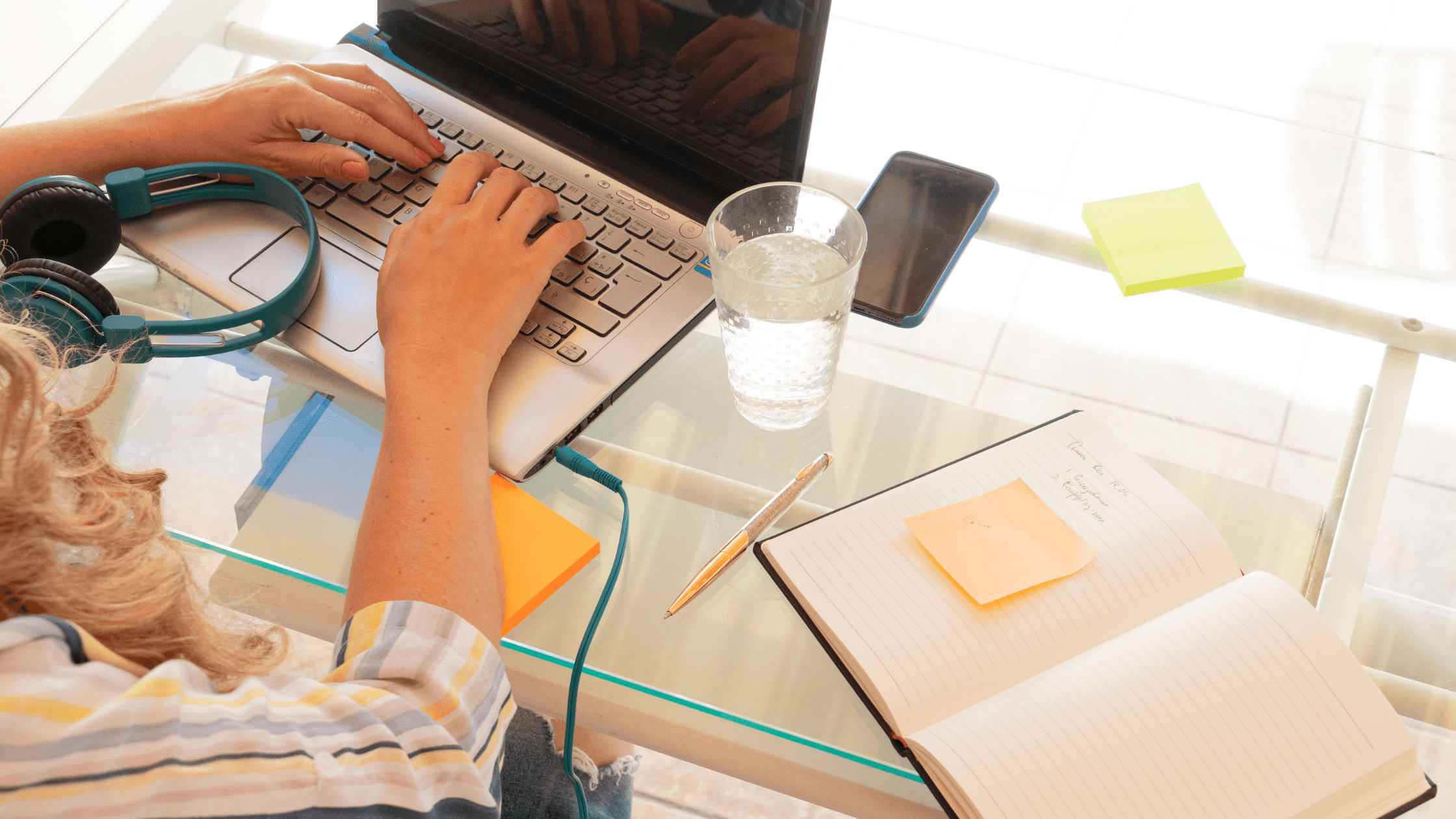 A Student using a laptop with a notebook and headphones for USMLE Step 2 CK