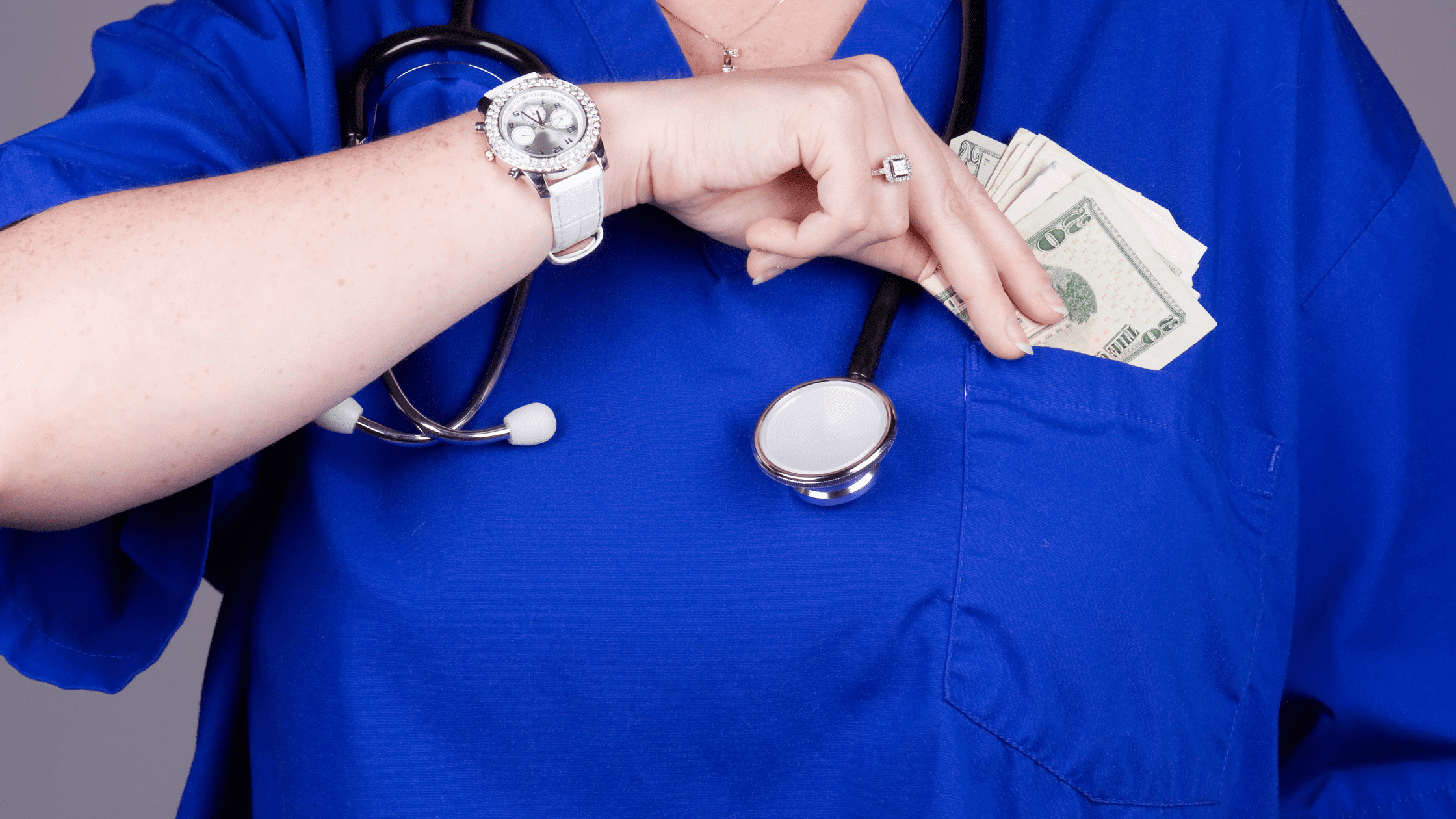 A medical school student in scrubs pulling a stack of money out of her shirt pocket.