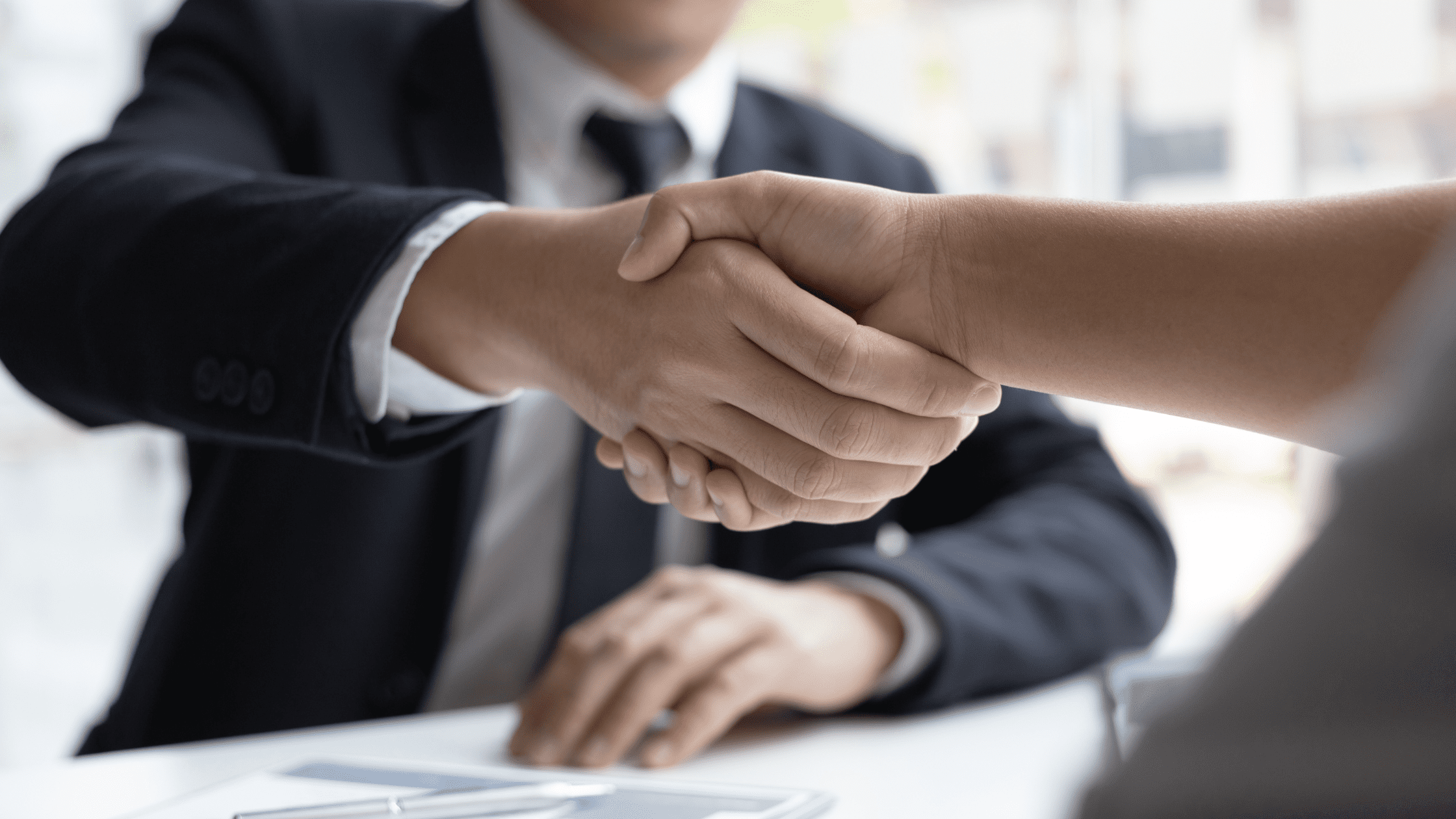 Two people shaking hands over desk for Medical School Interview.