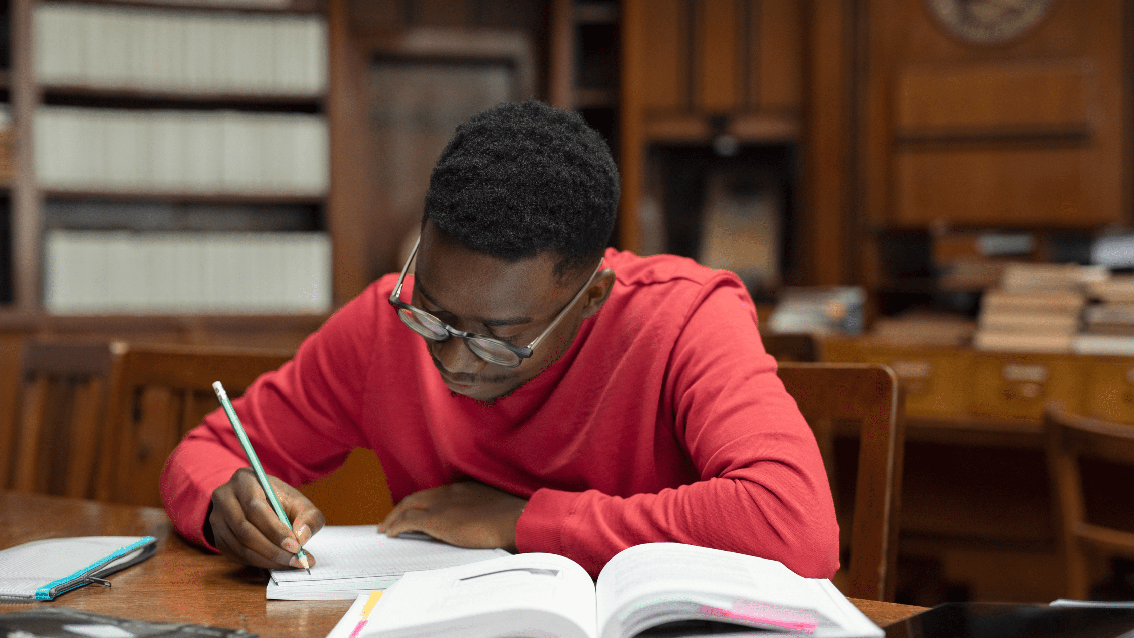 A student studying for the USMLE Step 2 in a library in front of medical textbooks.