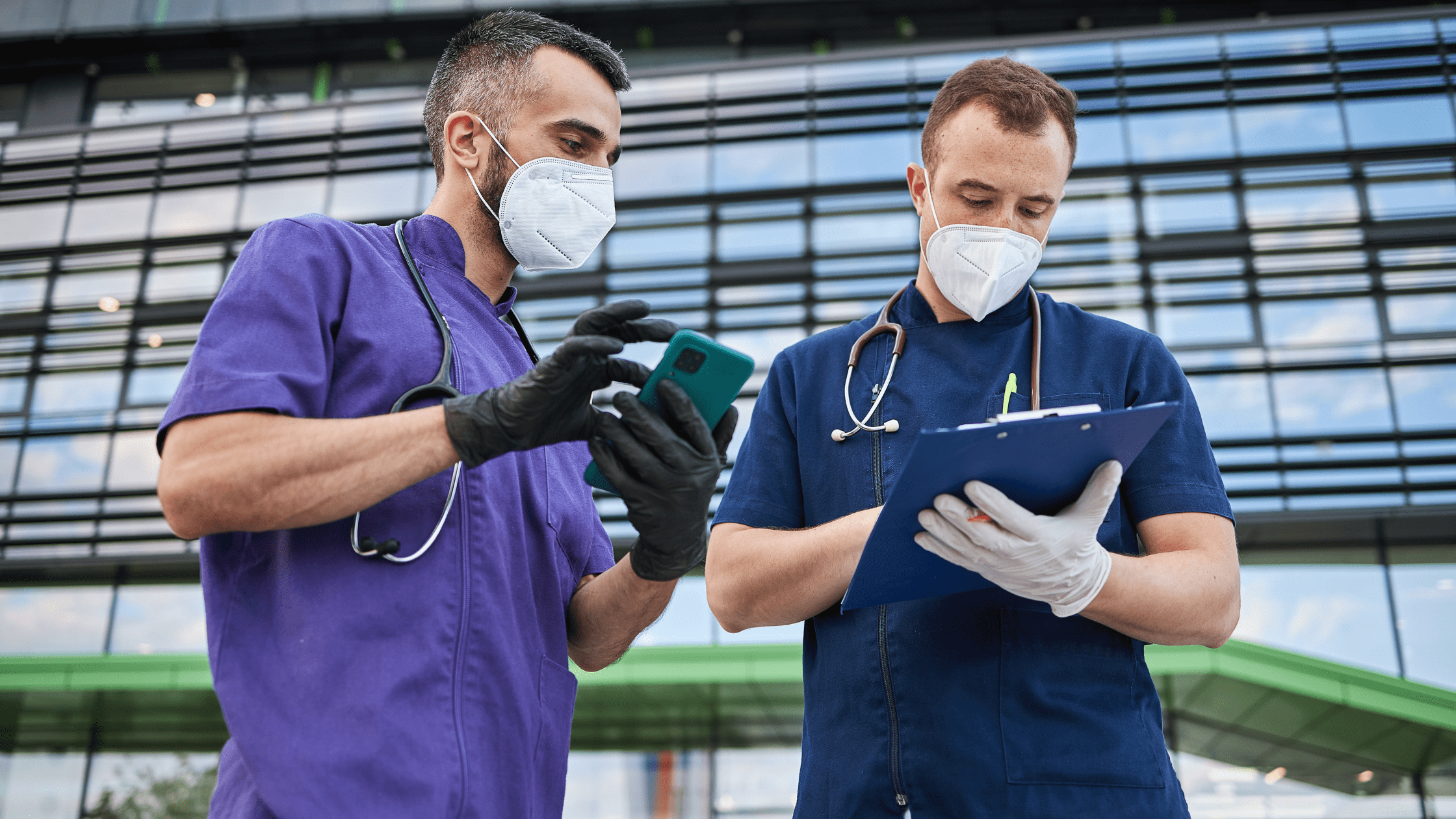 Two medical residents reviewing a document on a clipboard.