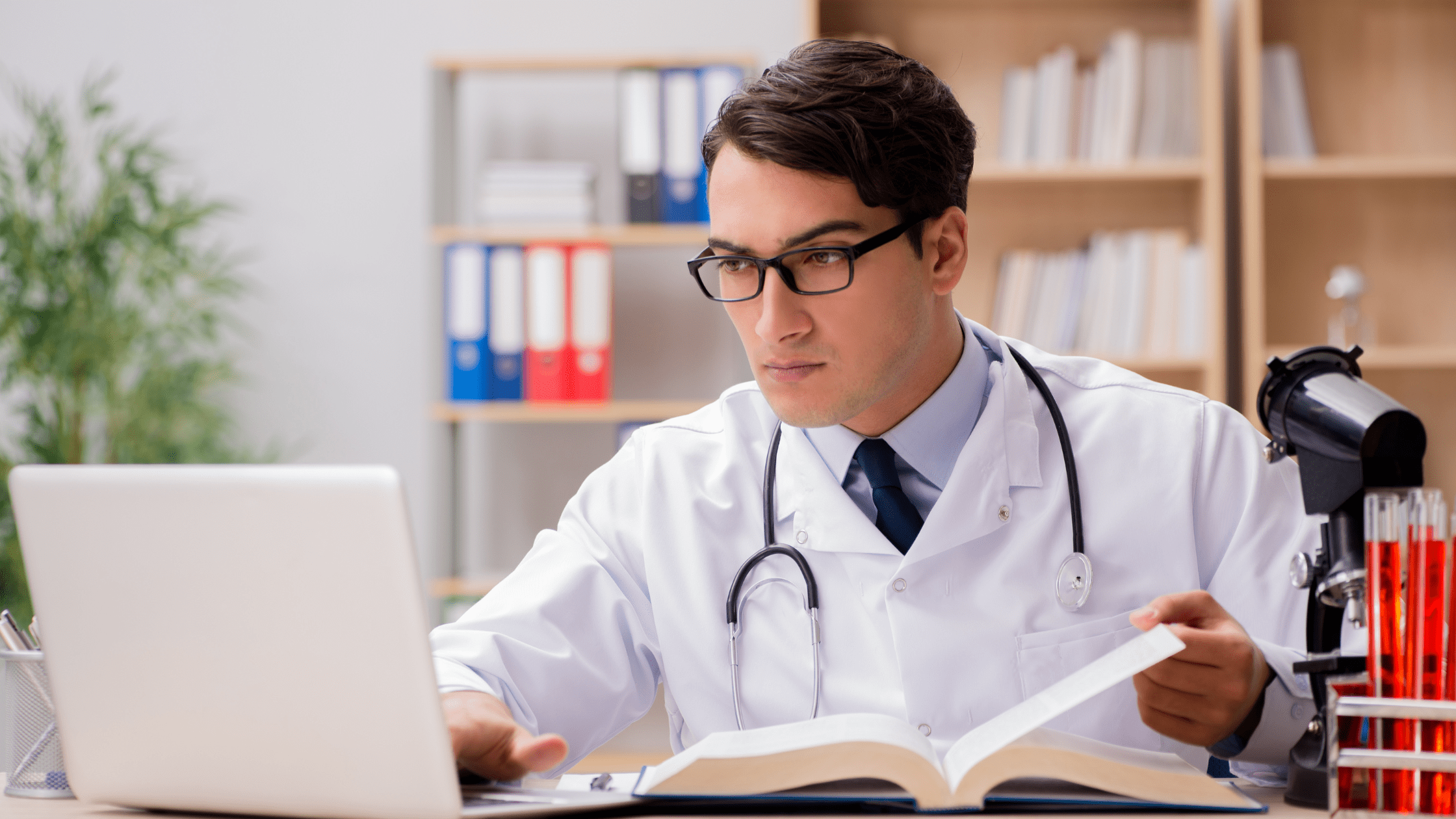 A medical resident studying for his Step 3 exam in front of a laptop and textbook.