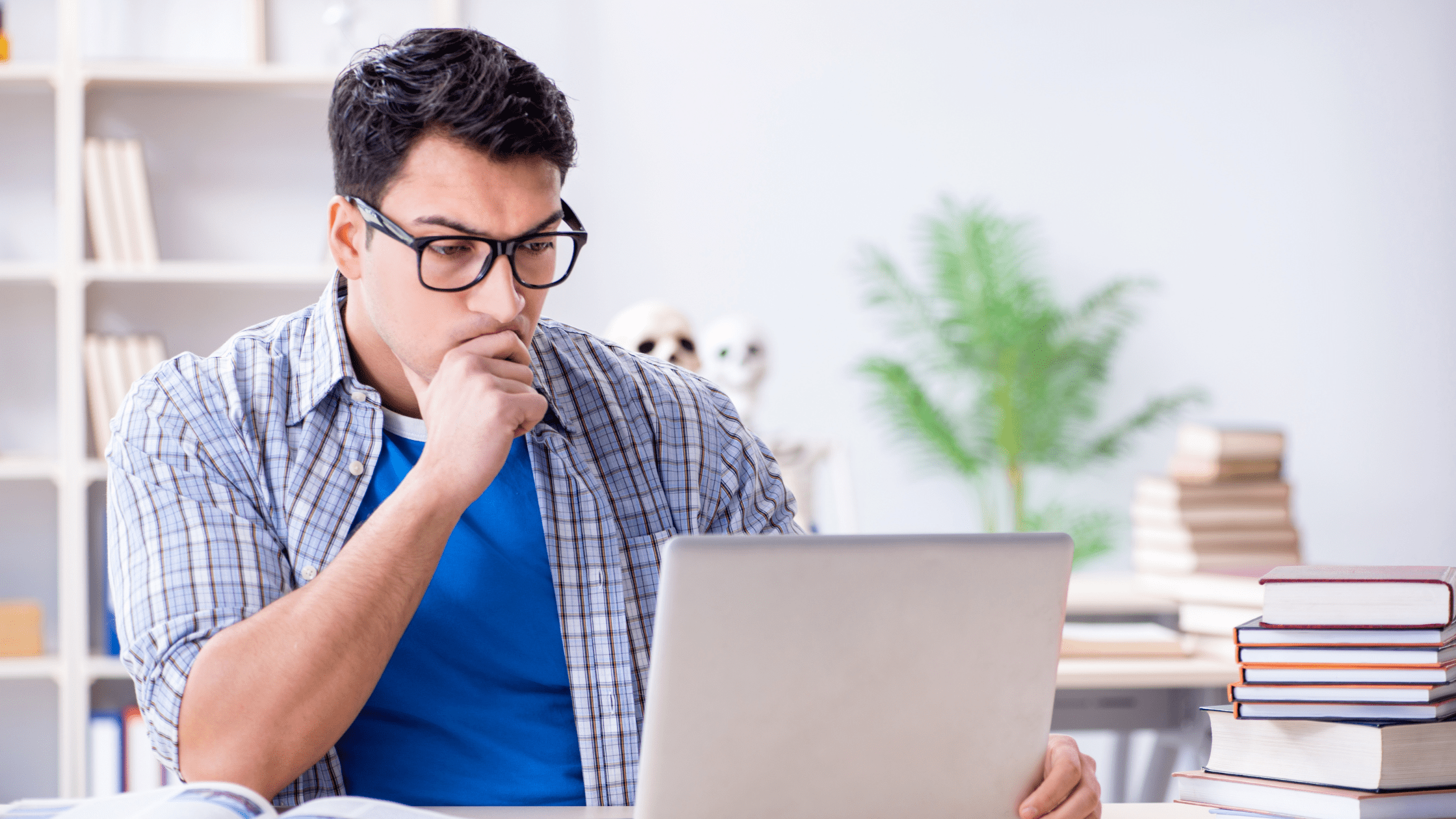 A medical school student looking through his NBME score report on a laptop to determine if he is ready for the USMLE exam.